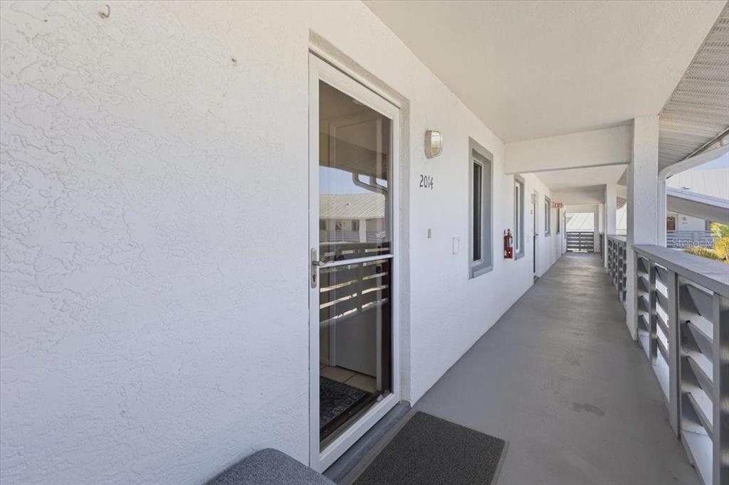 An exterior walkway with a white door labeled 2014 and a metal railing — 6800 PLACIDA ROAD UNIT 2014, ENGLEWOOD, FL