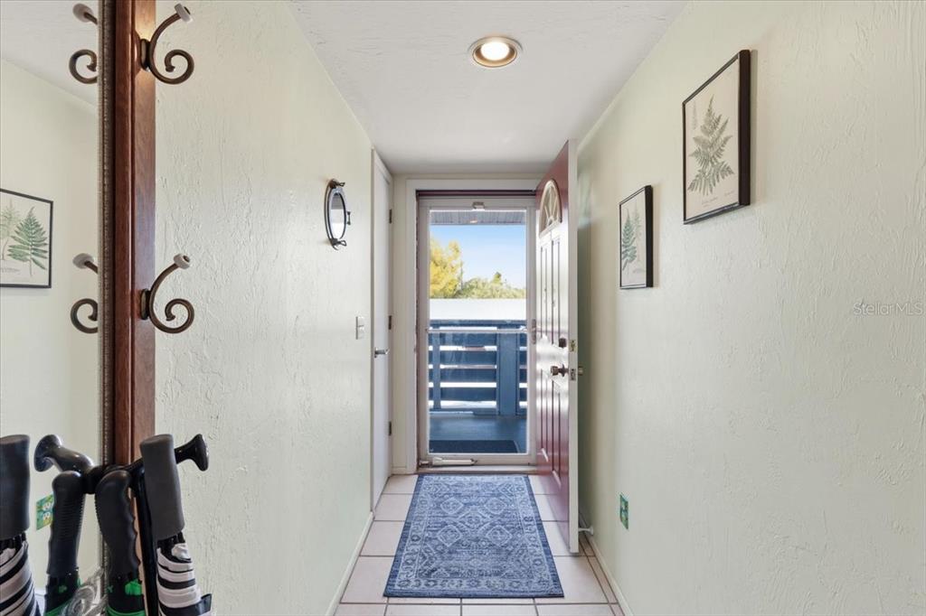 A narrow entryway features light walls, a tiled floor with a runner, and an open door — 6800 PLACIDA ROAD UNIT 2014, ENGLEWOOD, FL