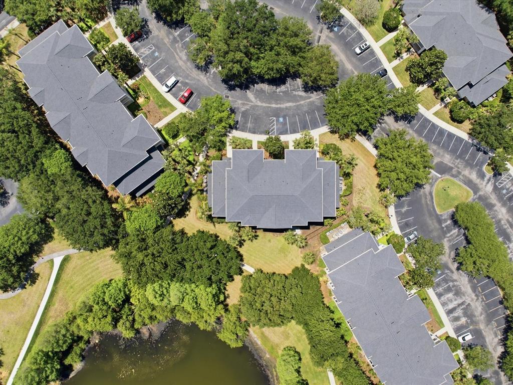 Aerial view of apartment buildings surrounded by trees, parking lots, and a small pond — 206 ANDROS AVENUE UNIT 15202, DAVENPORT, FL