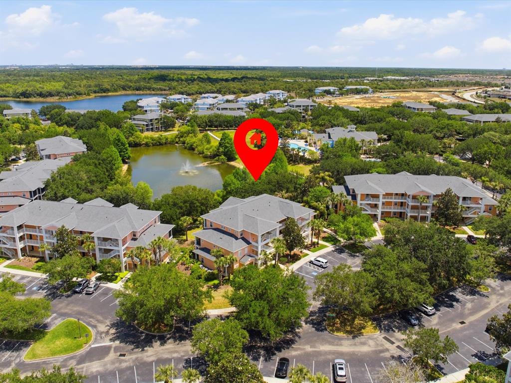 An aerial view shows multi-story apartment buildings surrounding a pond with a fountain — 206 ANDROS AVENUE UNIT 15202, DAVENPORT, FL