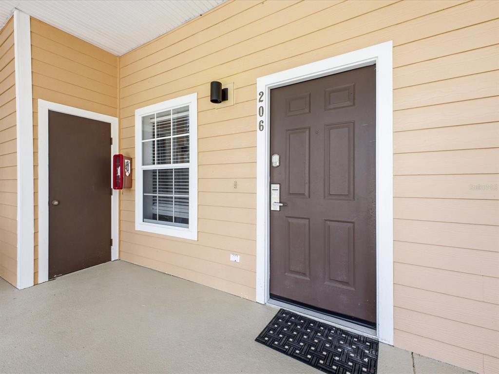An exterior view of a tan building entrance with a brown door labeled 206 — 206 ANDROS AVENUE UNIT 15202, DAVENPORT, FL