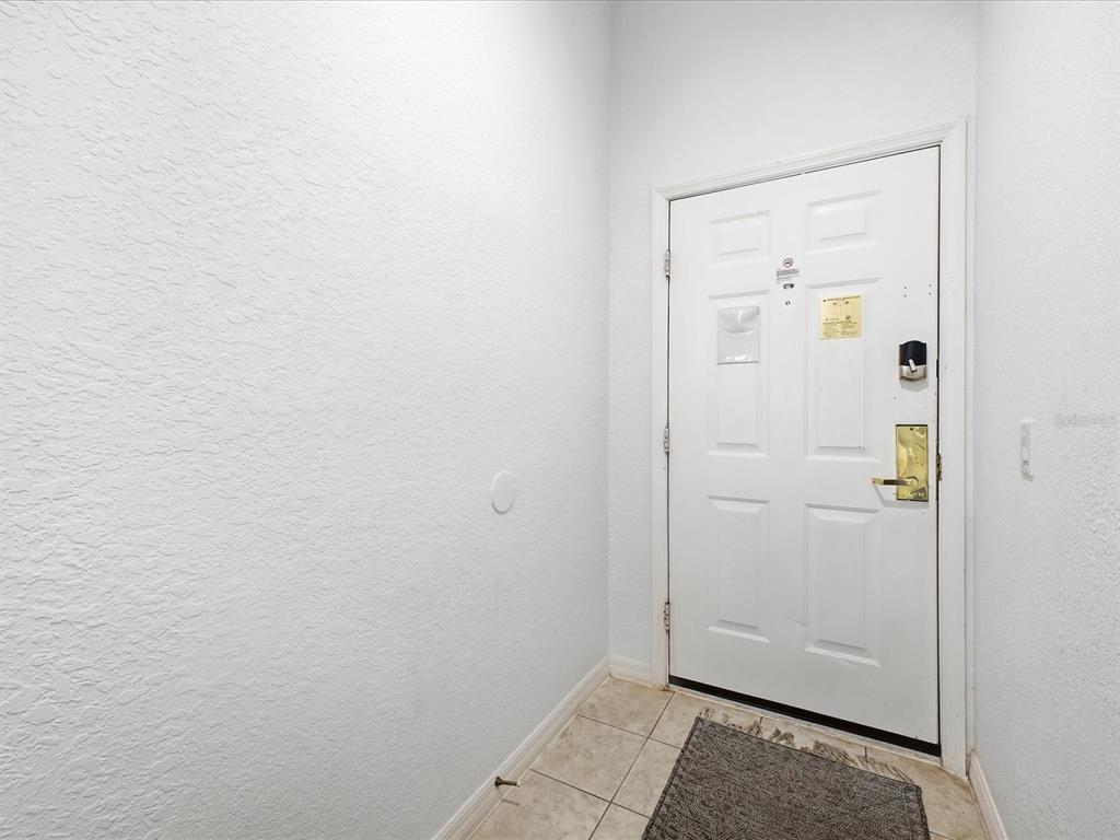 A white front door with a gold handle and smart lock opens into a tiled entryway — 206 ANDROS AVENUE UNIT 15202, DAVENPORT, FL