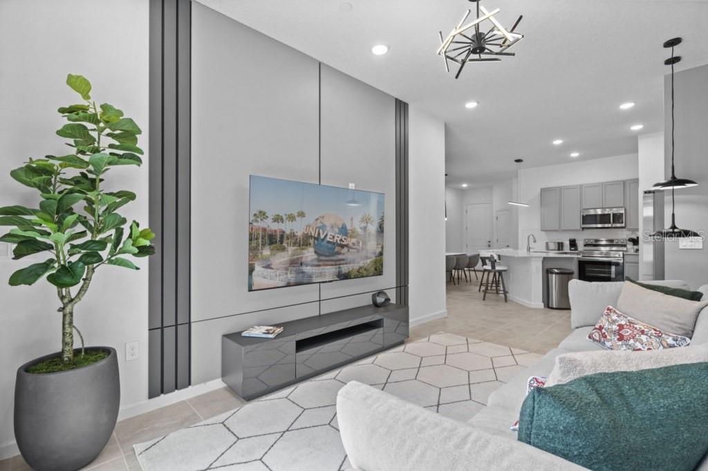 A modern living room features a gray accent wall with a mounted television and media console — 10424 EBB TIDE LANE, ORLANDO, FL