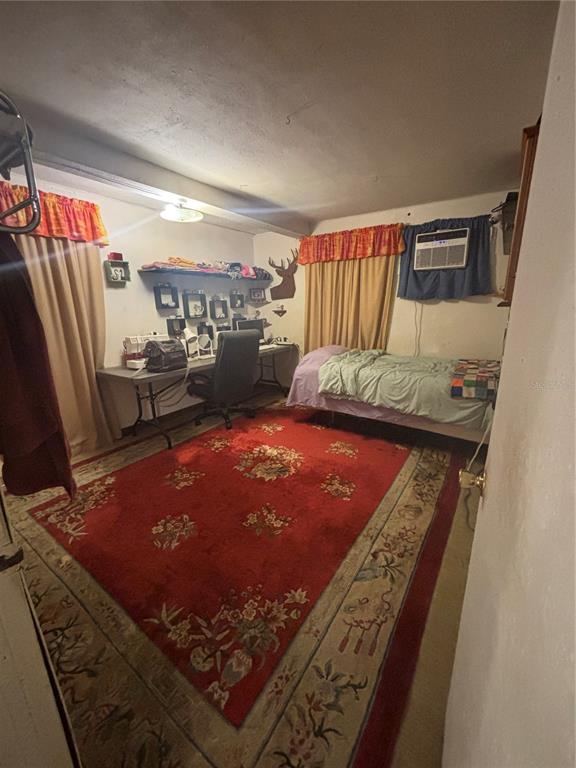 A bedroom featuring a desk, a single bed, a large red rug, and window curtains — 1811 BEACHWAY LANE, ODESSA, FL