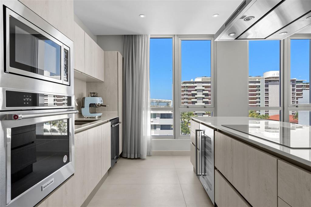 A modern kitchen features light wood cabinetry, stainless steel appliances, and large windows with city views — Condado Blu 14 DELCASSE ST, CONDADO UNIT 802, SAN JUAN, PR