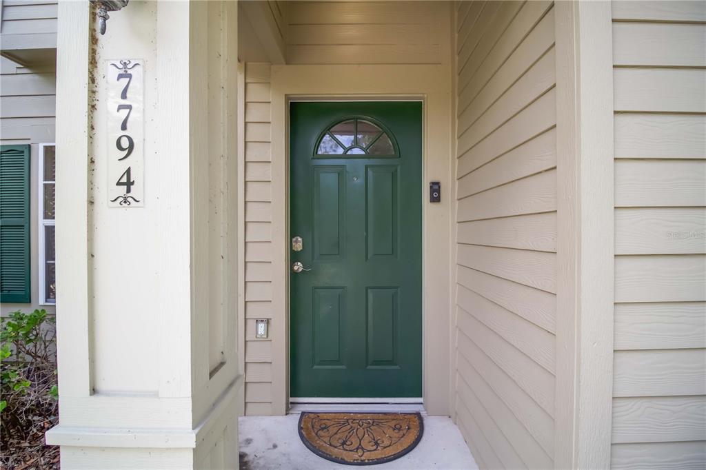 A green front door with a semi-circular window sits under a covered entryway — 7794 PLANTATION CIRCLE, BRADENTON, FL