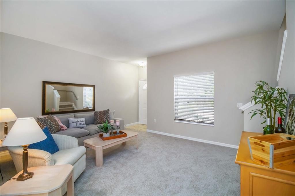 A living room with gray carpet, neutral walls, a sofa, an armchair, and a window — 7794 PLANTATION CIRCLE, BRADENTON, FL