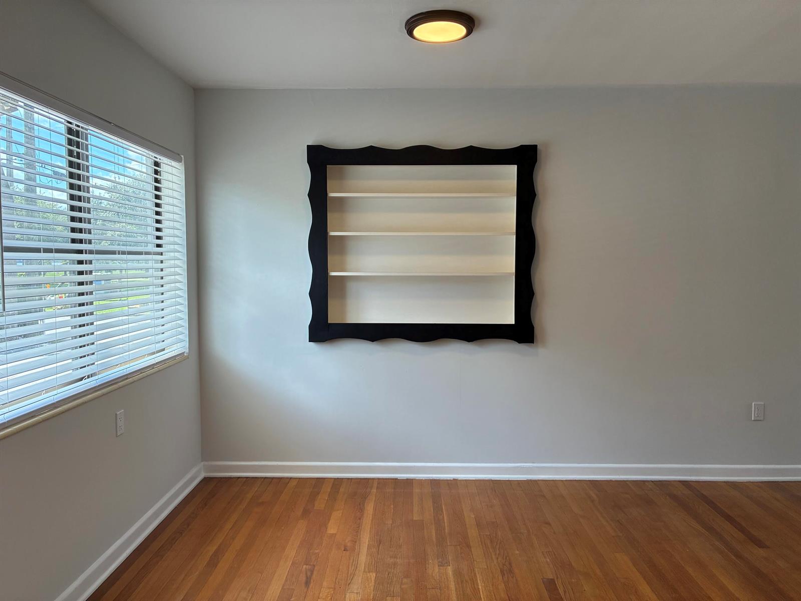 A room with hardwood floors, light gray walls, and a black-framed wall-mounted shelving unit — 130 S Lakeside Drive # 1, FL 33460, FL