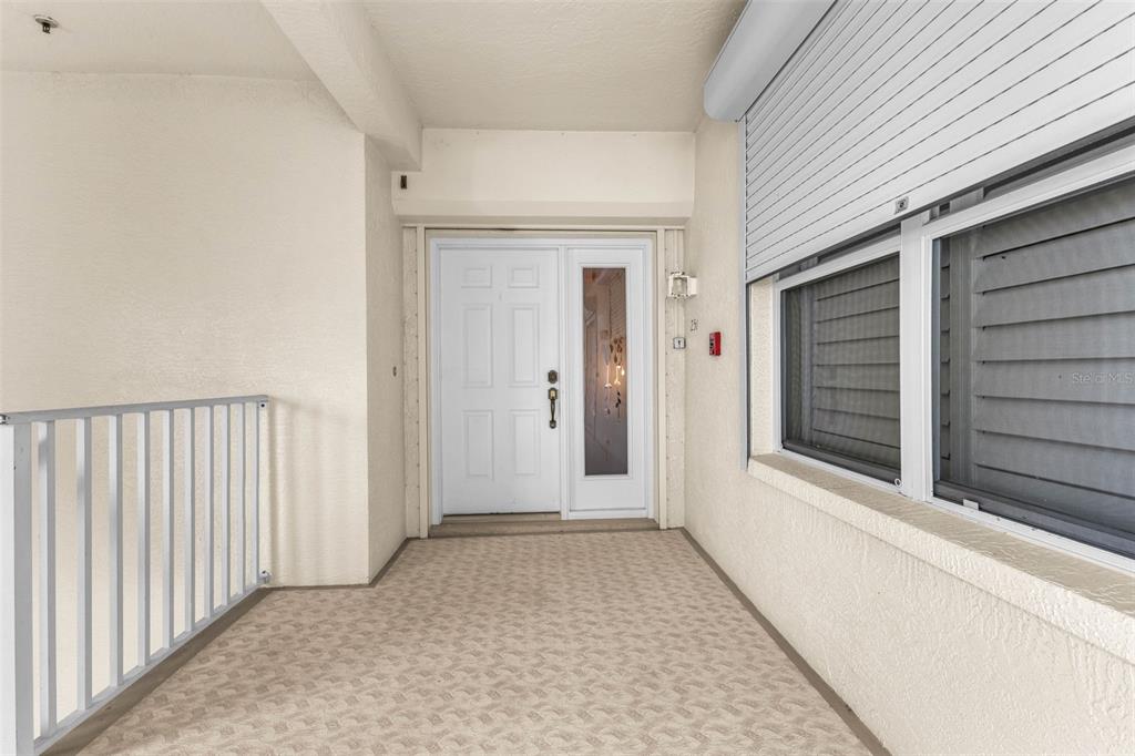 A covered entryway features a white front door with a side light and carpeted flooring — 200 HARBOR WALK DRIVE UNIT 251, PUNTA GORDA, FL