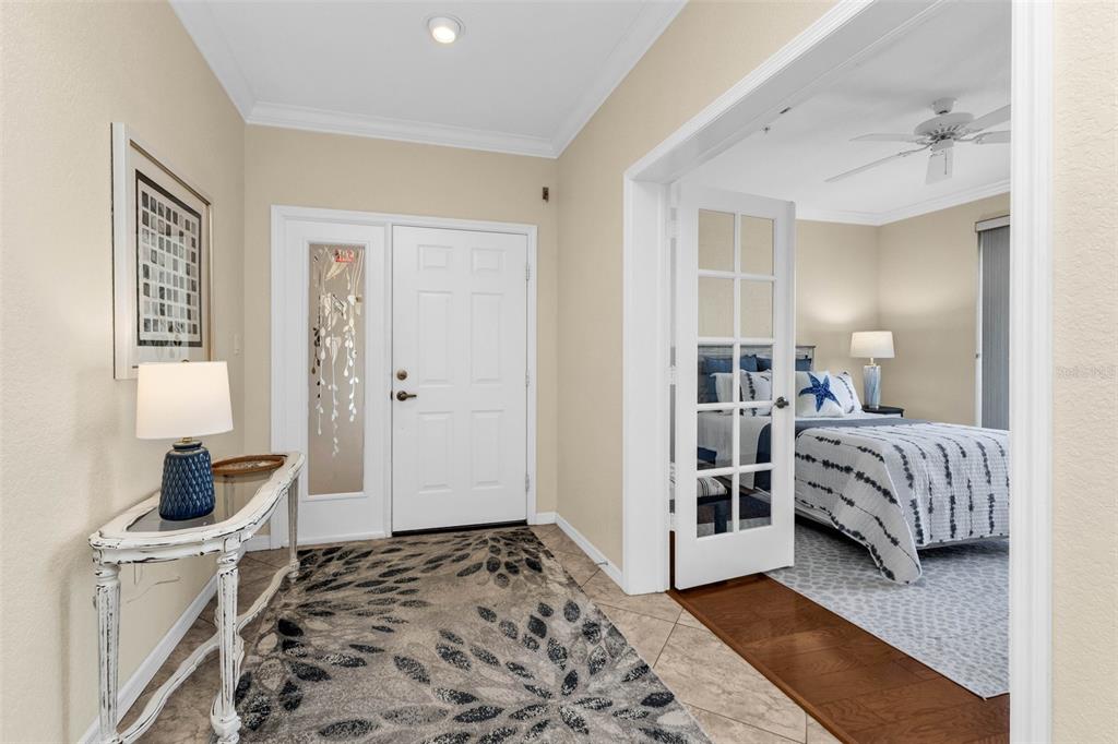 A foyer with tile flooring and a console table leads to a bedroom with French doors — 200 HARBOR WALK DRIVE UNIT 251, PUNTA GORDA, FL