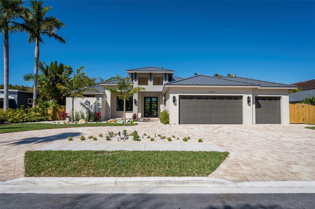 A modern single-story house with a metal roof, three-car garage, and paved driveway — 1959 WISTERIA STREET, SARASOTA, FL