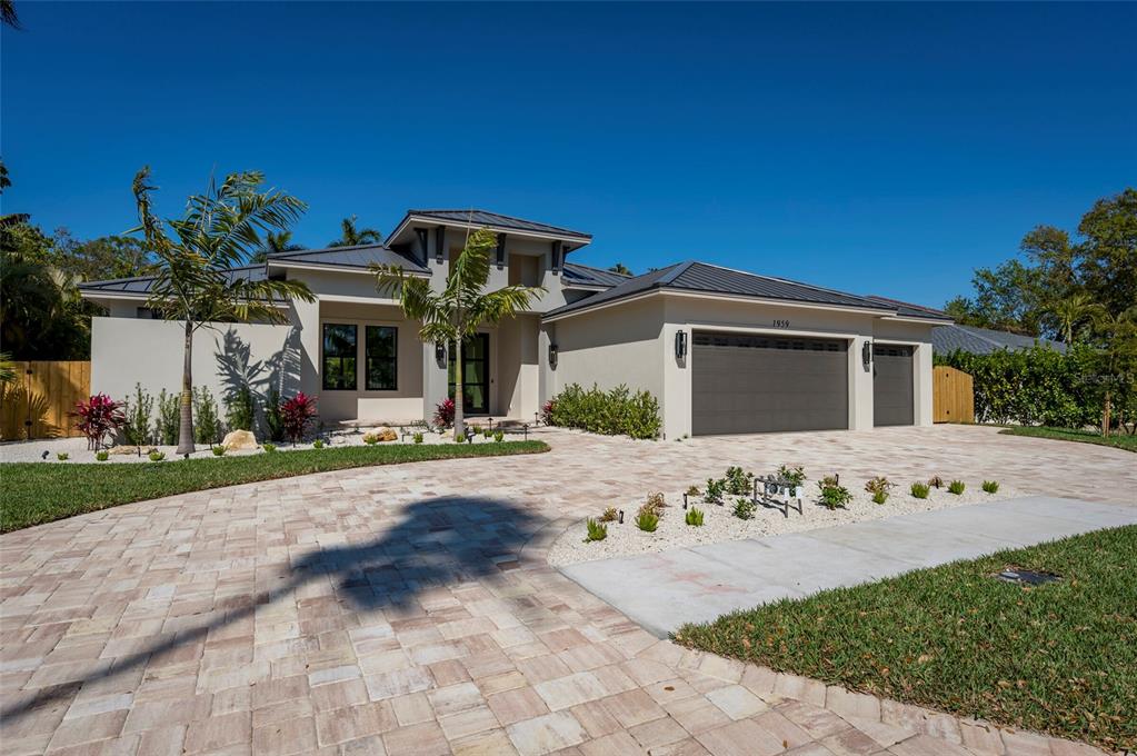 A modern single-story house with a metal roof, gray garage doors, and a paved driveway — 1959 WISTERIA STREET, SARASOTA, FL