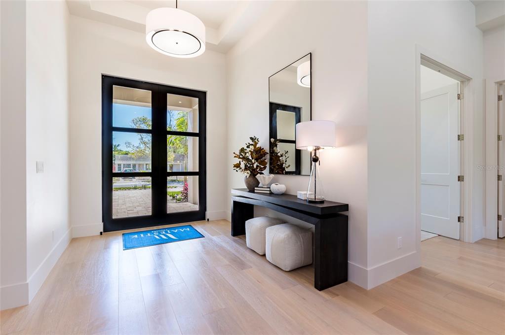 A bright entryway features light wood floors, a black console table, and a glass-paned door — 1959 WISTERIA STREET, SARASOTA, FL