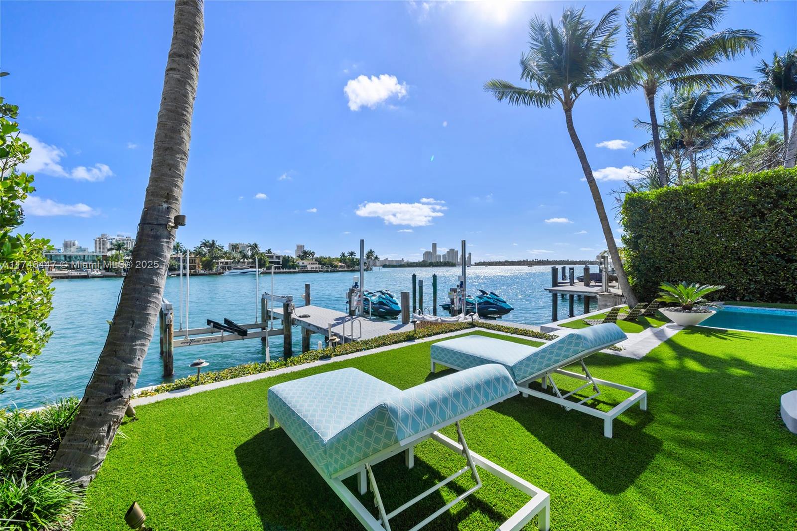 A waterfront backyard features a pool, lounge chairs, and a private dock with jet skis — 227 E DILIDO DR, Miami Beach FL 33139, MIAMI BEACH, FL
