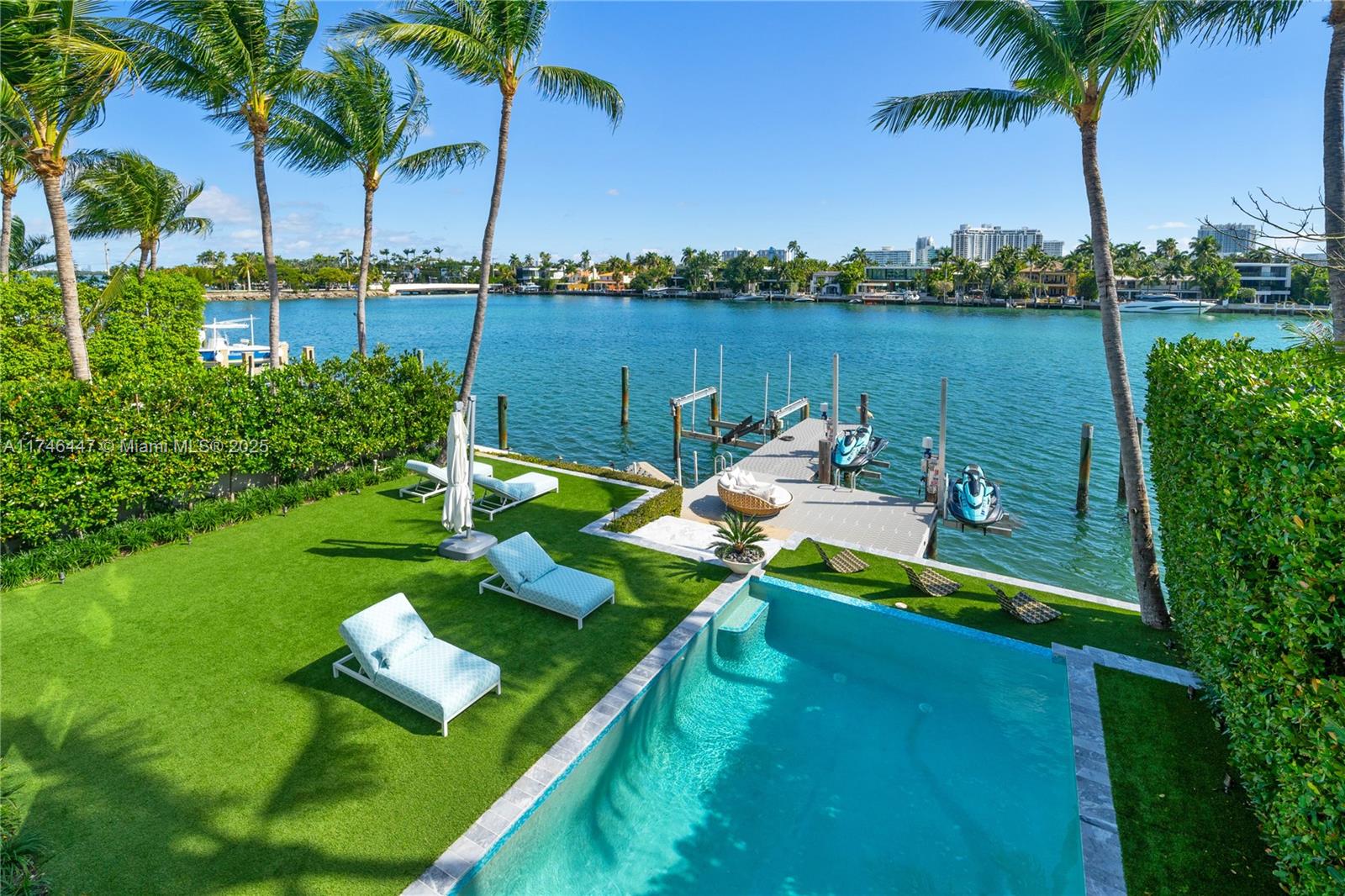 An outdoor backyard features a swimming pool, lounge chairs, and a private dock on water — 227 E DILIDO DR, Miami Beach FL 33139, MIAMI BEACH, FL