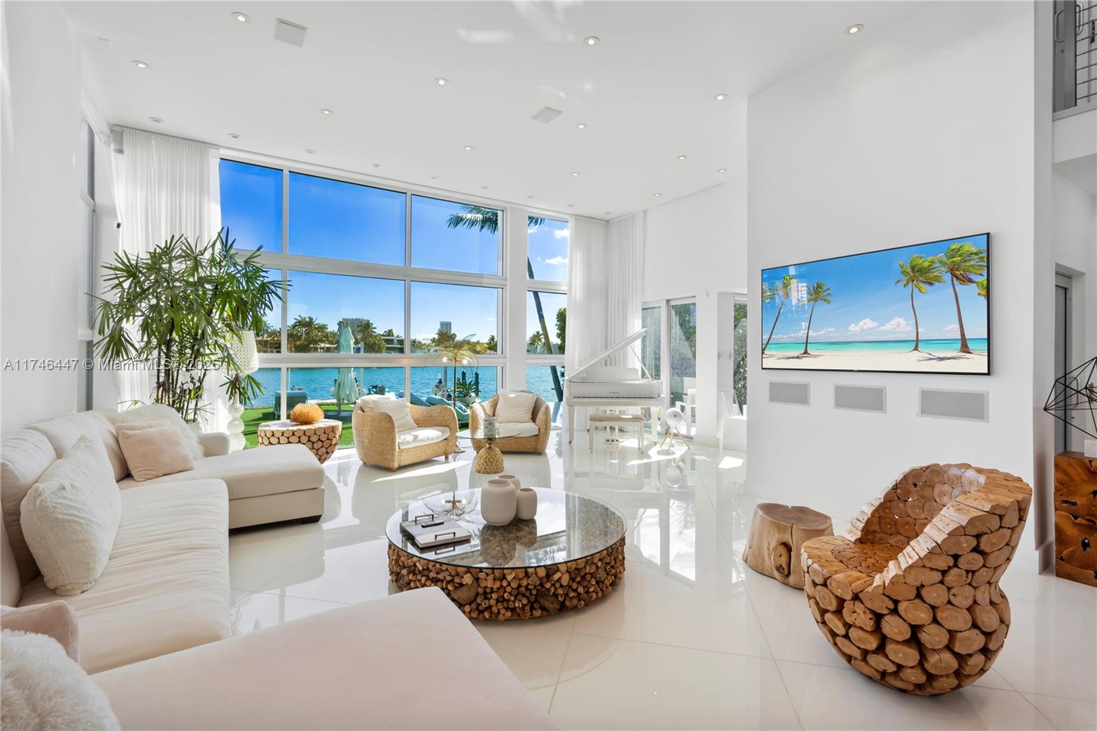 A bright, modern living room features white tile floors, a grand piano, and floor-to-ceiling windows — 227 E DILIDO DR, Miami Beach FL 33139, MIAMI BEACH, FL