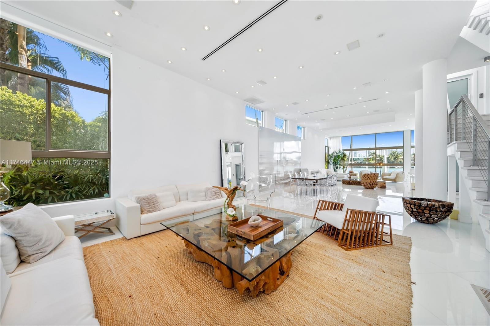 A bright, modern living room features white walls, tile floors, and a large glass-topped coffee table — 227 E DILIDO DR, Miami Beach FL 33139, MIAMI BEACH, FL
