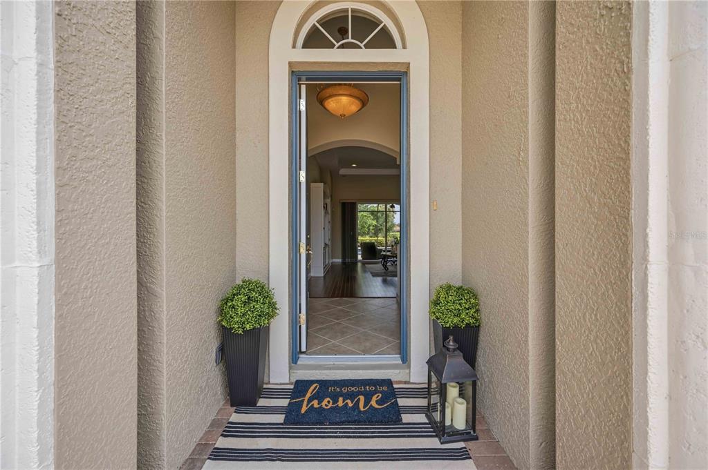An entryway features a blue front door, a welcome mat, and two potted plants — 170 MONTELLUNA DRIVE, NORTH VENICE, FL