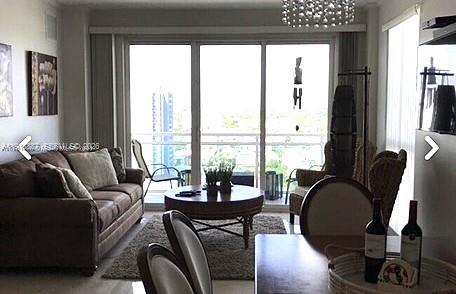 A living room features a brown sofa, a round coffee table, and a balcony view — 6917 Collins Ave, Miami Beach FL 33141, MIAMI BEACH, FL