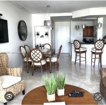 A dining area and kitchen with tile floors, a round coffee table, and bar stools — 6917 Collins Ave, Miami Beach FL 33141, MIAMI BEACH, FL