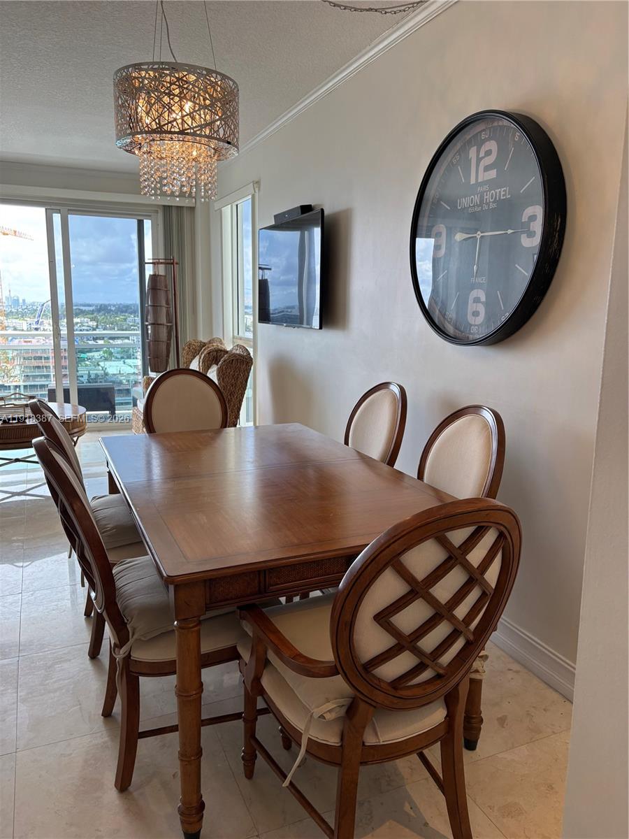 A dining room features a wooden table, six chairs, a large wall clock, and a chandelier — 6917 Collins Ave, Miami Beach FL 33141, MIAMI BEACH, FL