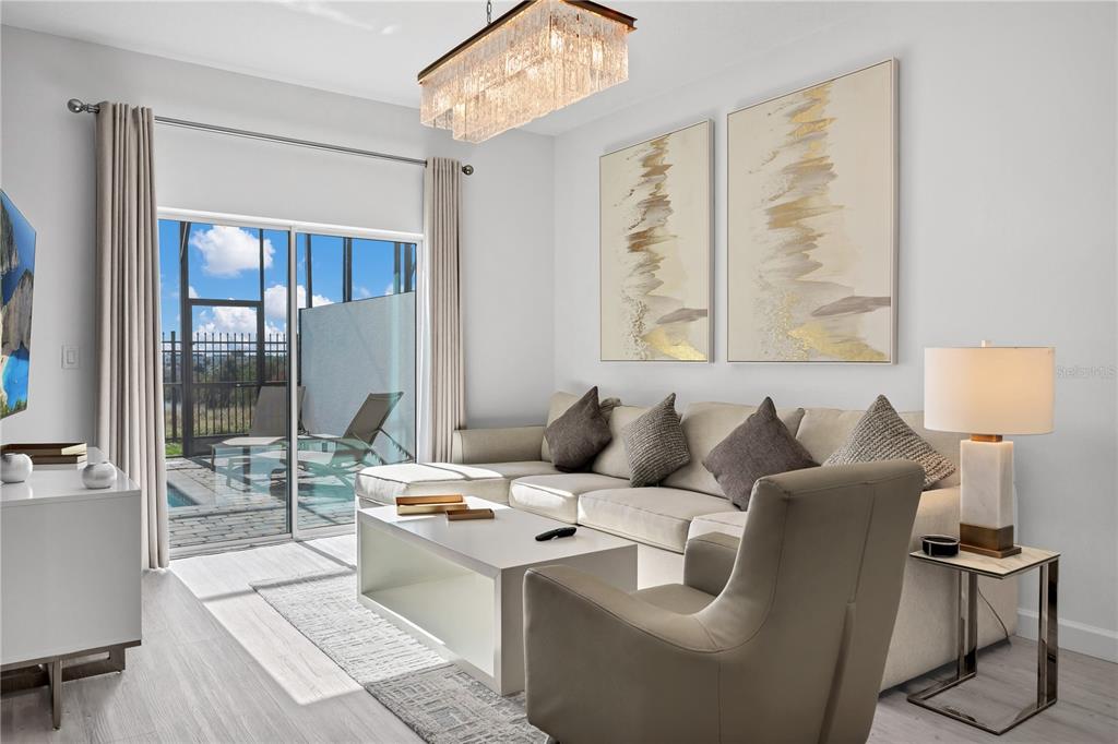A living room features a sectional sofa, a coffee table, and sliding doors to a pool — 412 FAMAGUSTA DRIVE, DAVENPORT, FL