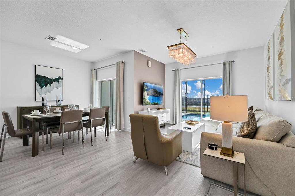 A living and dining area features light wood floors, a pool view, and modern furnishings — 412 FAMAGUSTA DRIVE, DAVENPORT, FL