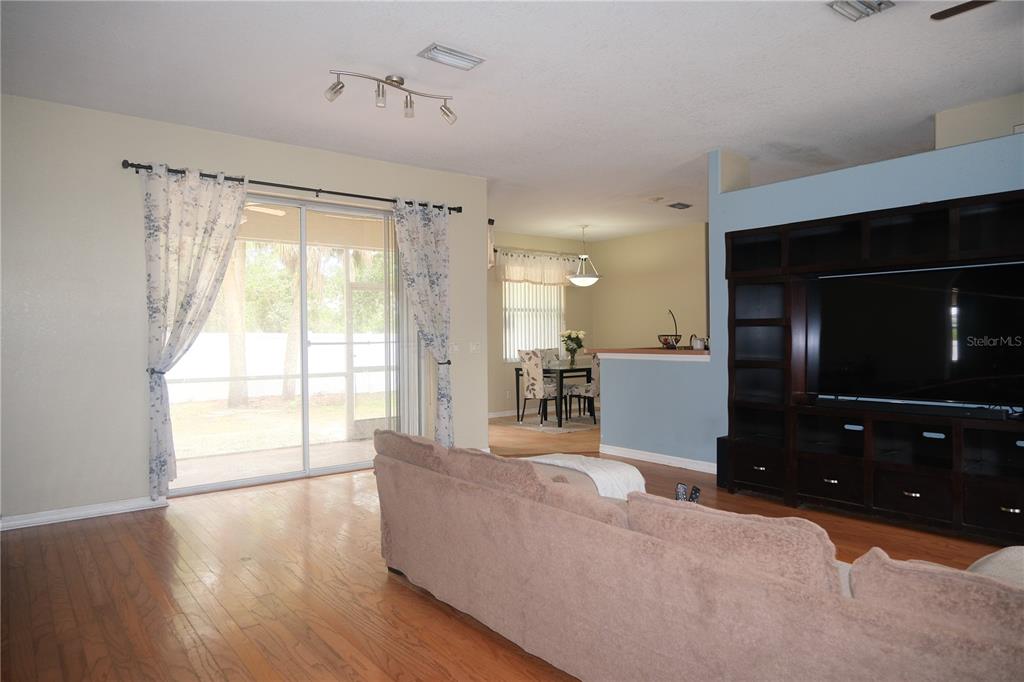 A living room with hardwood floors, a large entertainment center, and sliding glass doors — 4491 CUTHBERT AVENUE, NORTH PORT, FL