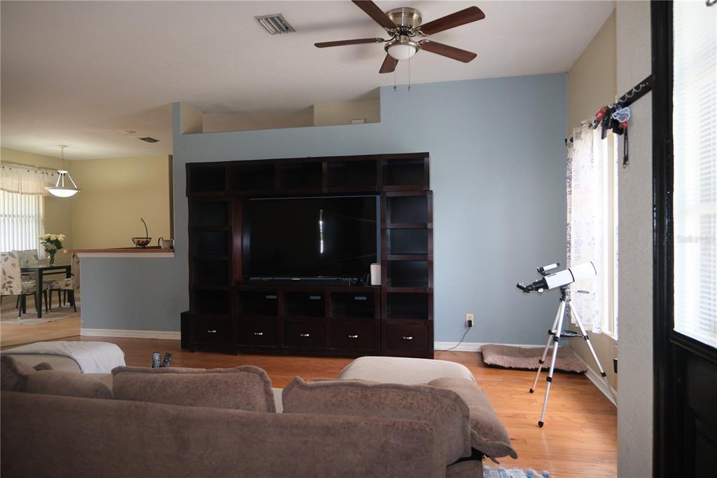 A living room features a large dark wood entertainment center, a telescope, and hardwood floors — 4491 CUTHBERT AVENUE, NORTH PORT, FL