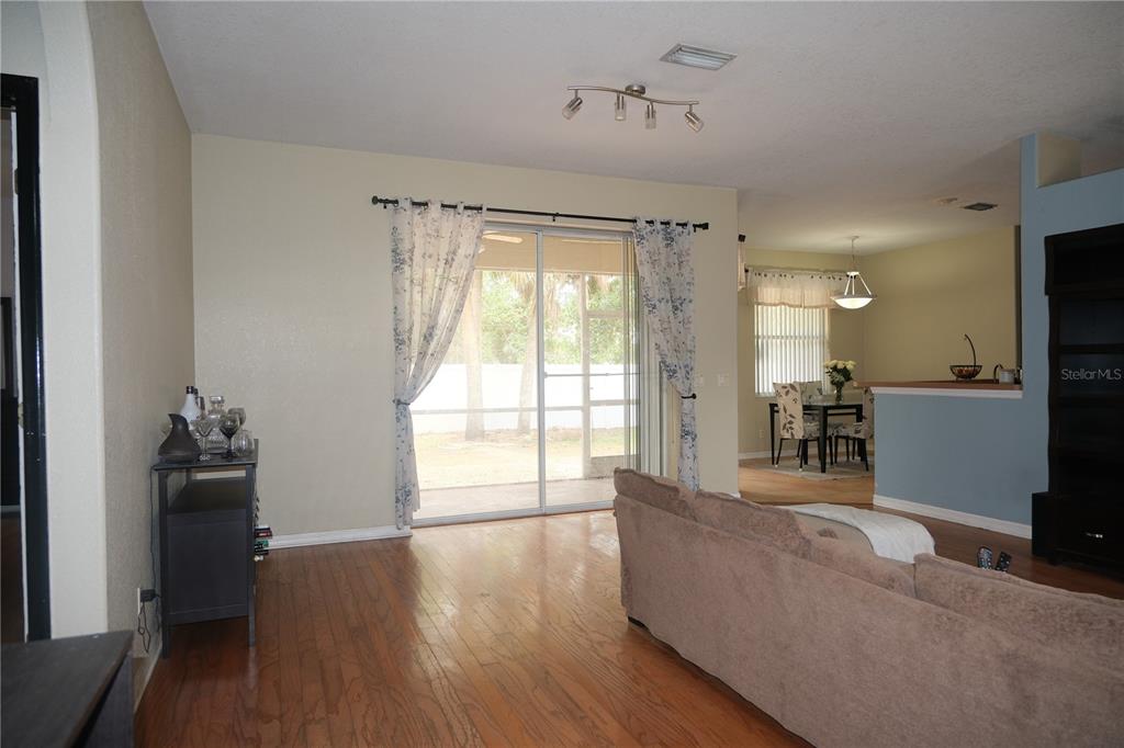 A living room with hardwood floors, a sliding glass door, and an adjacent dining area — 4491 CUTHBERT AVENUE, NORTH PORT, FL