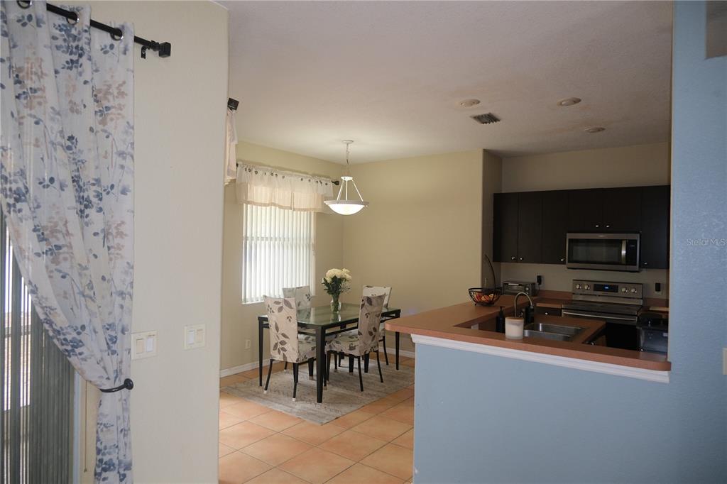 A dining area with a glass table and chairs sits adjacent to a kitchen — 4491 CUTHBERT AVENUE, NORTH PORT, FL