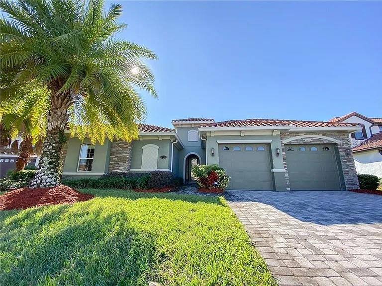 A single-story house with a palm tree, stone accents, and a paved driveway — 2810 SWOOP CIRCLE, KISSIMMEE, FL