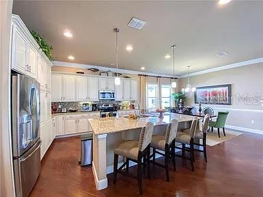 A kitchen with white cabinets, granite countertops, a center island, and an adjacent dining area — 2810 SWOOP CIRCLE, KISSIMMEE, FL