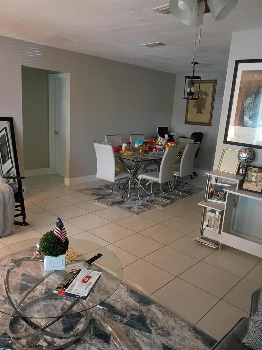 A dining area with a glass table and white chairs sits adjacent to a living room — 1270 NW 66th Terrace, Margate FL 33063, MARGATE, FL