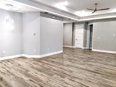 An open-concept room features light gray walls, wood-look flooring, and a tray ceiling with lighting — 52 ETHAN ALLEN DRIVE, PALM COAST, FL