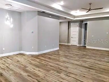 An empty room features light gray walls, wood-look flooring, a tray ceiling, and a ceiling fan — 52 ETHAN ALLEN DRIVE, PALM COAST, FL