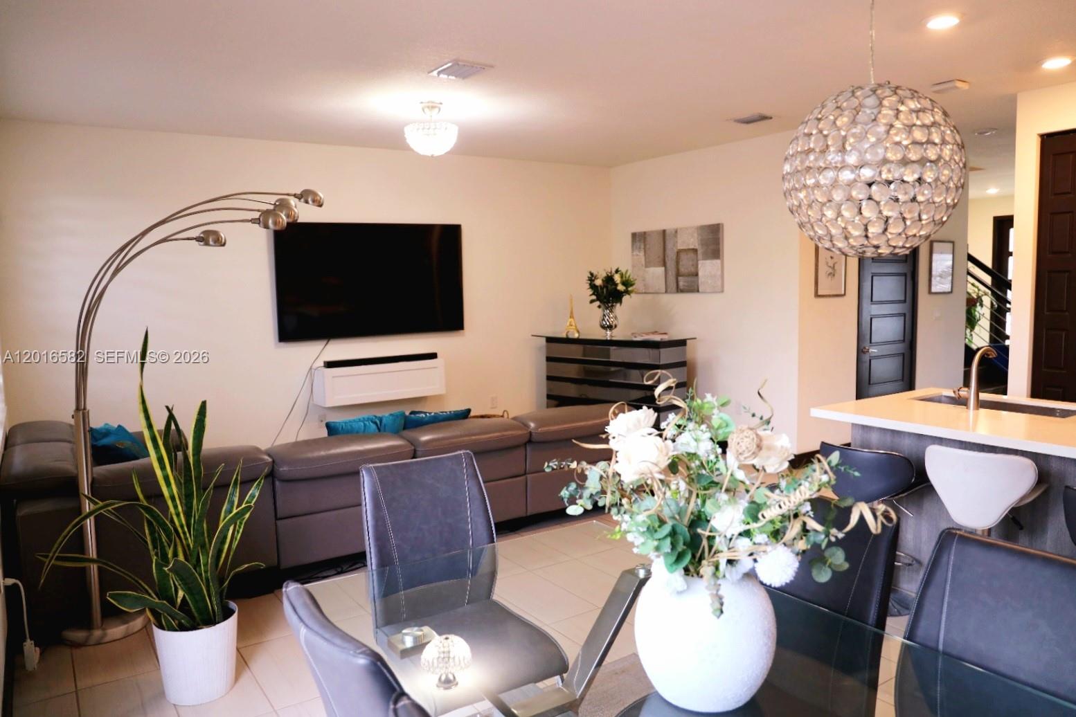 An entryway features a mirrored console table, a blue velvet chair, and a wooden staircase — 16012 NW 91st Ct, Miami Lakes FL 33018, MIAMI LAKES, FL