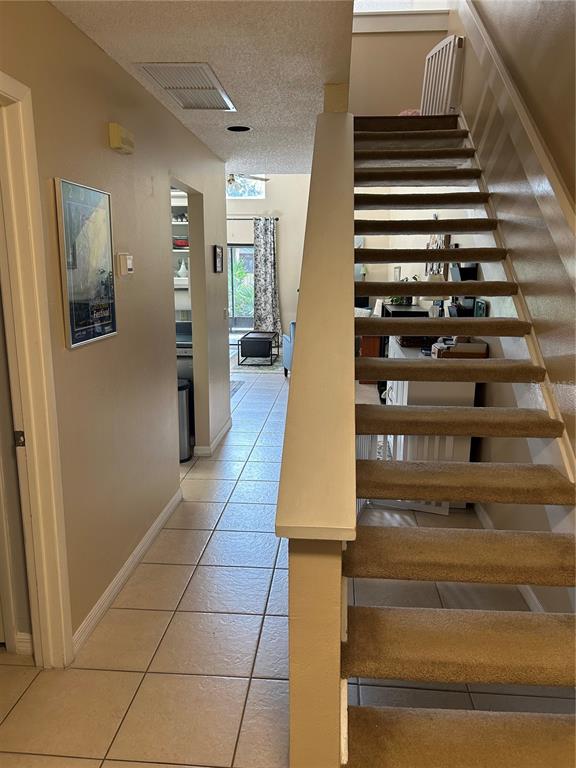 A tiled hallway leads to a living area past a carpeted staircase with a railing — 499 CLUB DRIVE, WINTER SPRINGS, FL