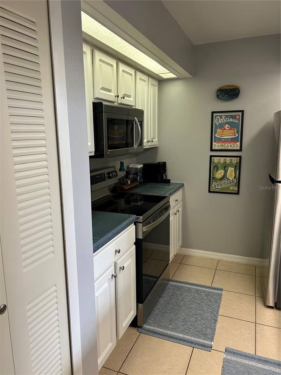 A kitchen features white cabinets, stainless steel appliances, and a tiled floor — 499 CLUB DRIVE, WINTER SPRINGS, FL