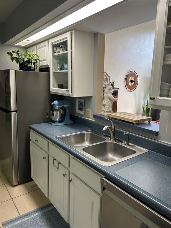 A kitchen features white cabinets, blue laminate countertops, a double sink, and stainless steel appliances — 499 CLUB DRIVE, WINTER SPRINGS, FL