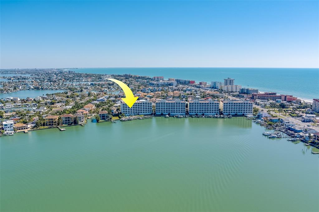 An aerial view shows a large waterfront apartment complex with a yellow arrow pointing down — 17745 GULF BOULEVARD UNIT 303, REDINGTON SHORES, FL