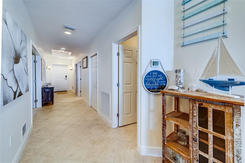 A bright hallway features tile flooring, white doors, and coastal-themed decor on a wooden cabinet — 17745 GULF BOULEVARD UNIT 303, REDINGTON SHORES, FL