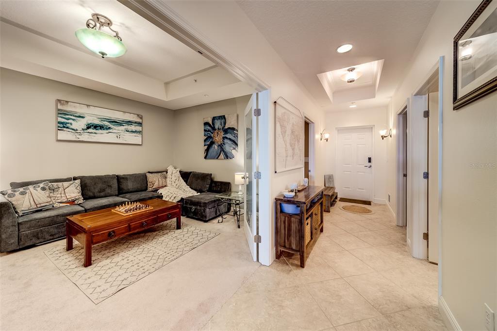 A living room with a gray sectional sofa and a wooden coffee table near an entryway — 17745 GULF BOULEVARD UNIT 303, REDINGTON SHORES, FL