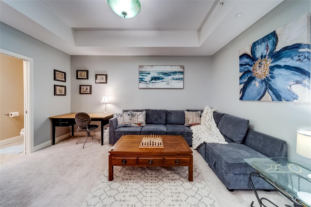 A living room features a blue sectional sofa, a wooden coffee table, and a desk area — 17745 GULF BOULEVARD UNIT 303, REDINGTON SHORES, FL