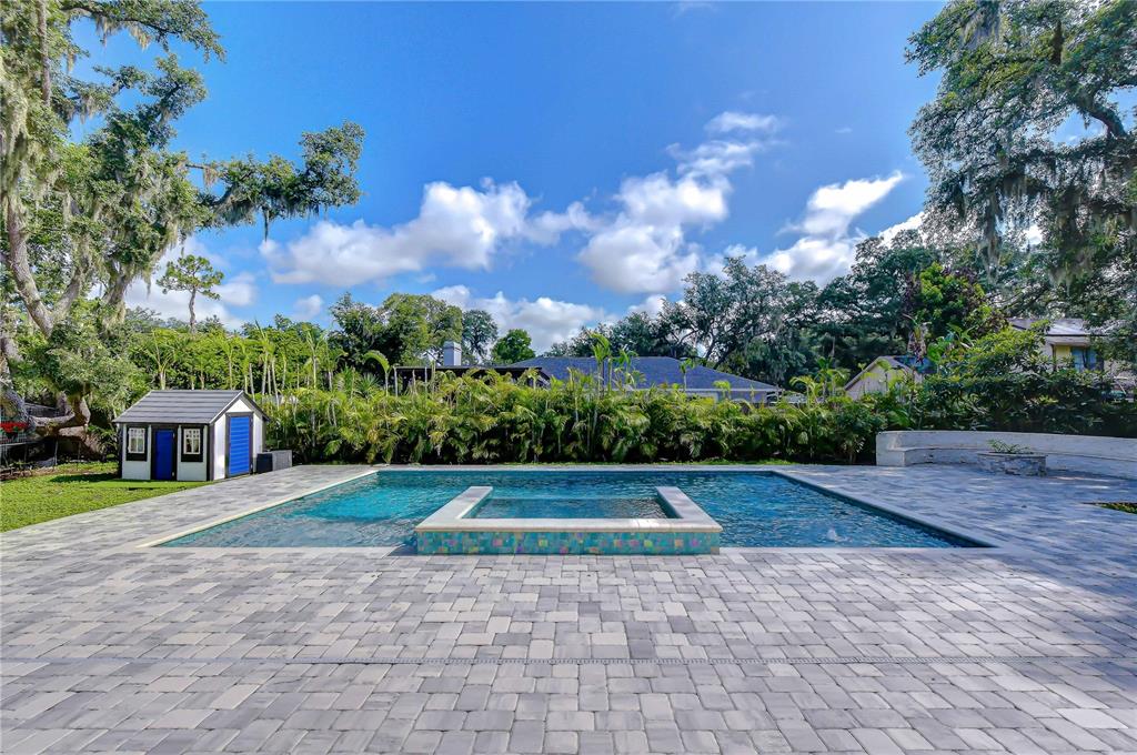 A backyard features a swimming pool with a spa, lounge chairs, and mature trees — 106 BAYFIELD DRIVE, BRANDON, FL