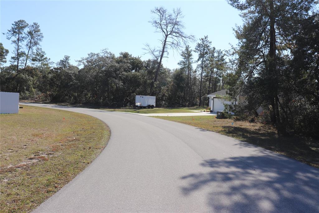 A paved road curves past a grassy lot with a white trailer and a garage — TBD SW 157TH STREET, OCALA, FL