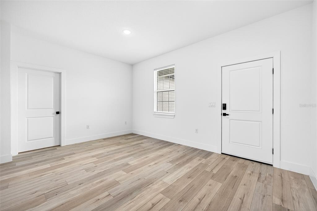 An empty room with white walls, light wood-look flooring, a window, and two white doors — 6223 EMMONSDALE STREET, PORT CHARLOTTE, FL
