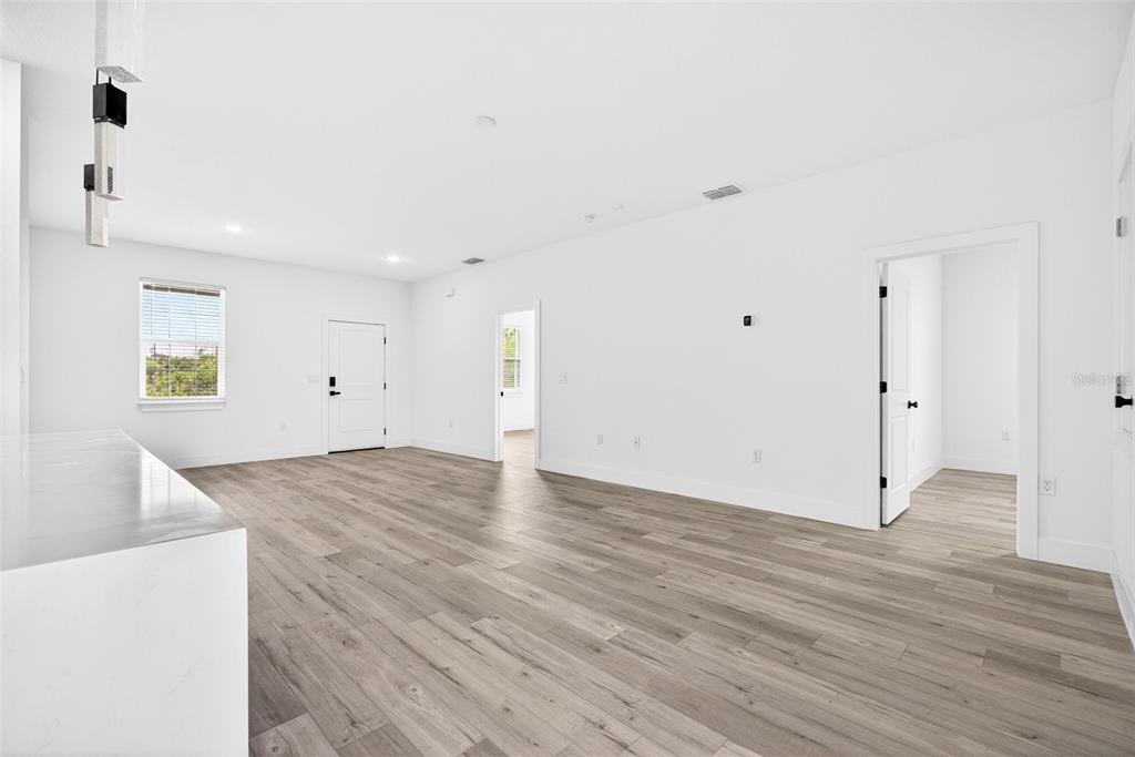 An open-concept living area features white walls, light wood-look flooring, and multiple doorways — 6223 EMMONSDALE STREET, PORT CHARLOTTE, FL