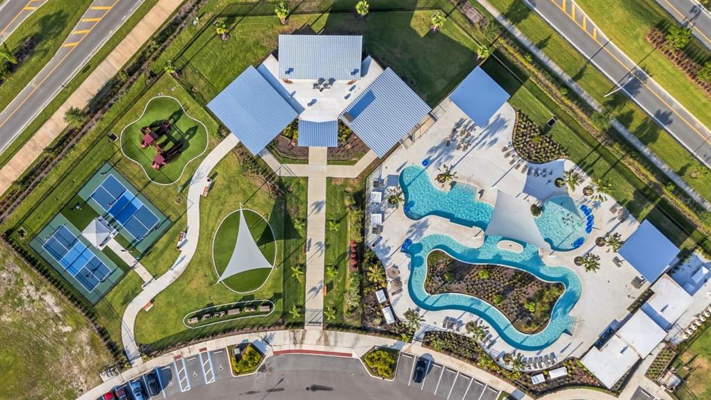 An aerial view shows a community center with a pool, playground, and sports courts — 5841 RIVERSTON AVENUE, WESLEY CHAPEL, FL