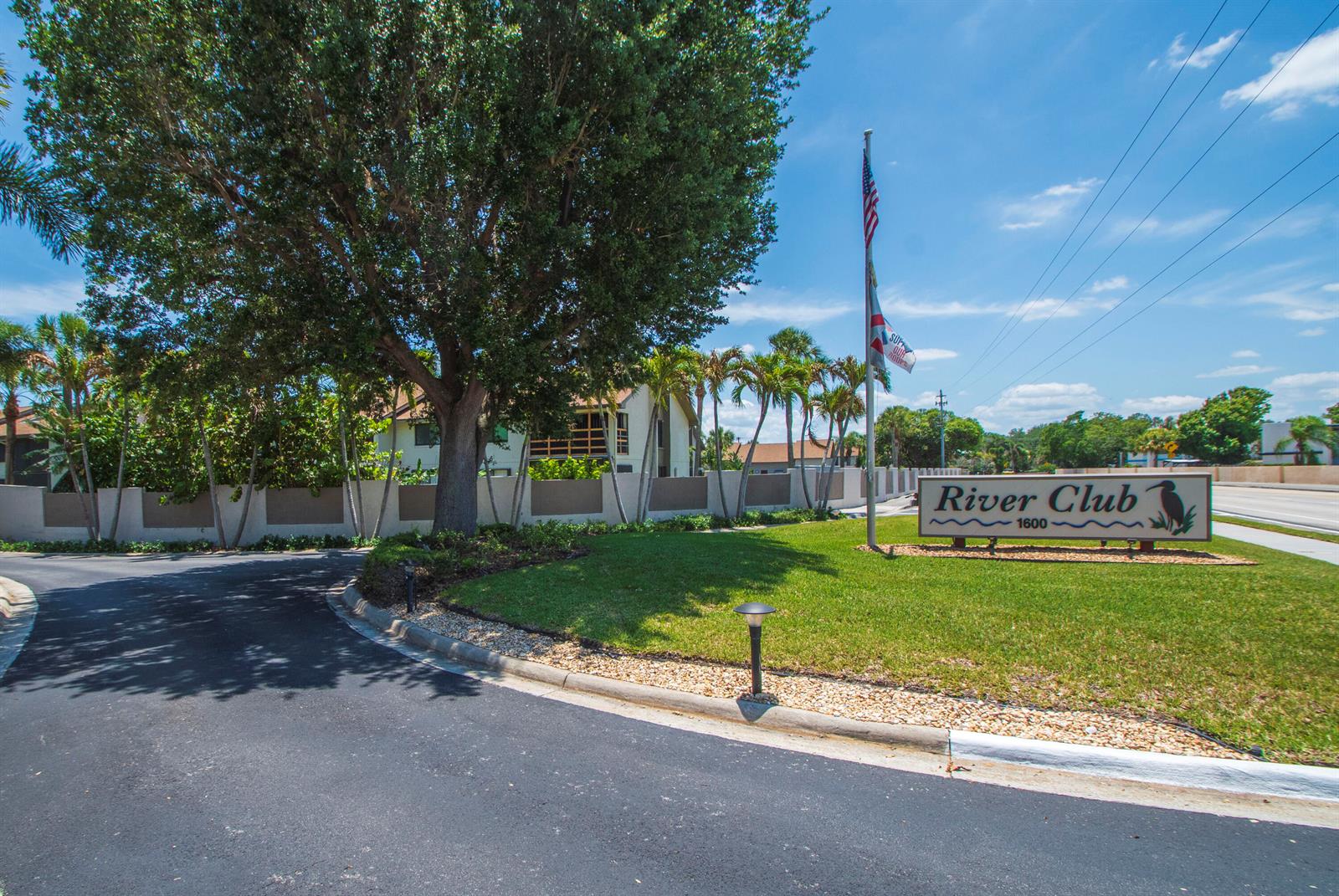 A sign for River Club stands on a grassy lawn near a paved entrance road — 1600 NE Dixie Highway # 103, Jensen Beach FL 34957, JENSEN BEACH, FL